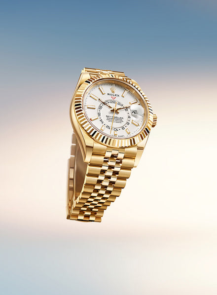 A gold Rolex watch with a white dial and date display, set against a gradient blue and beige background.