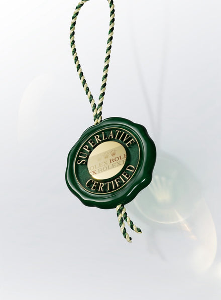 Green and gold Rolex “Superlative Certified” seal hanging by a green and white braided string.