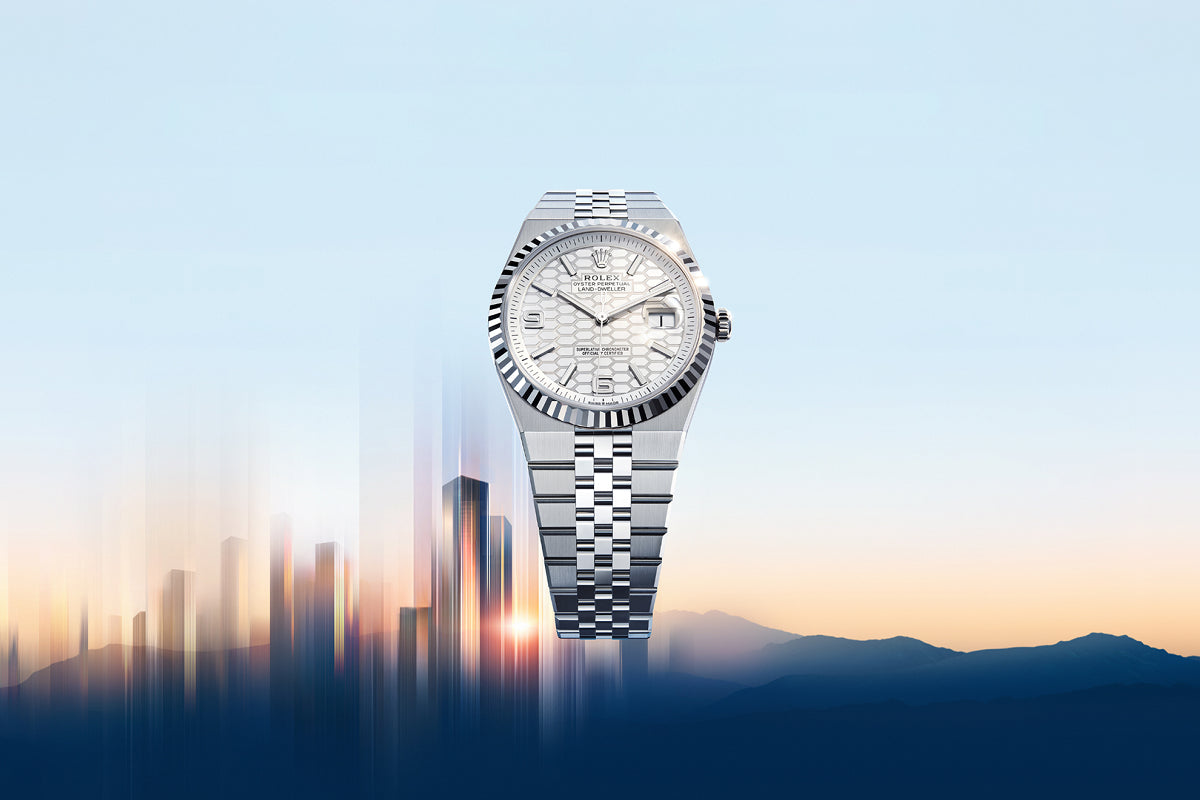 A silver luxury wristwatch floats above a blurred city skyline at sunrise with mountains in the background.