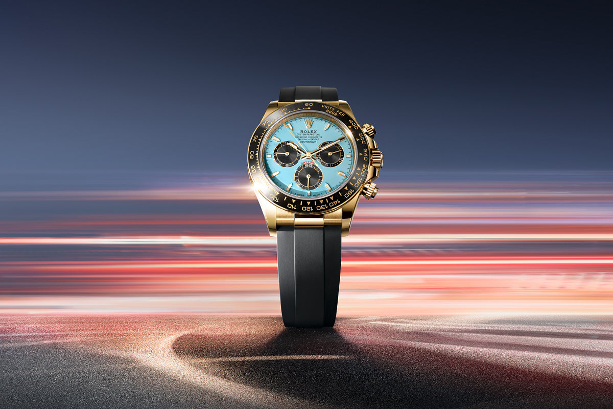 A gold wristwatch with a blue face and black strap, set against a blurred, dynamic background.