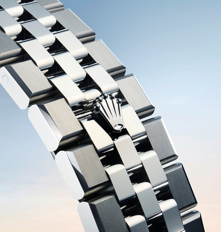 Close-up of a silver Rolex watch bracelet with the Rolex crown logo against a blue gradient background.