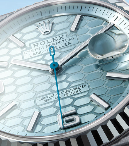 Close-up of a Rolex Oyster Perpetual watch face with a blue hexagonal pattern and silver markers.