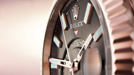 Close-up of a Rolex watch face showing detailed hands, markers, and the iconic Rolex crown logo.
