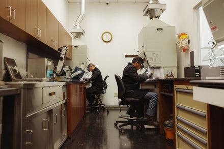 Two watch makers working at desks in a polishing work room