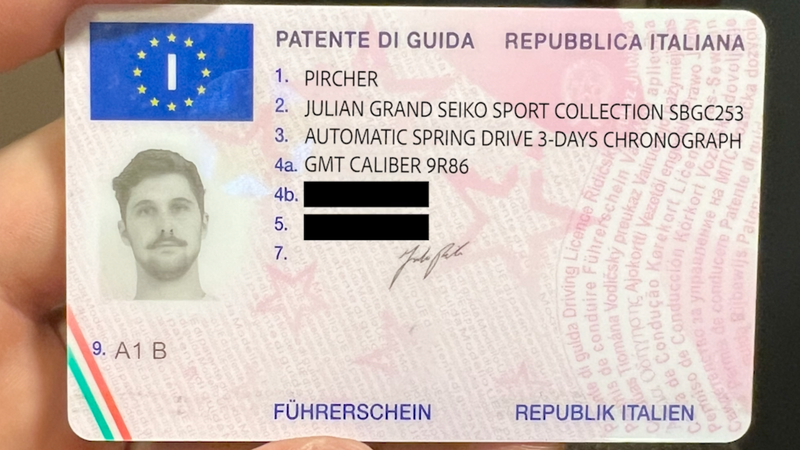 An Italian drivers license held by a hand, with personal details and a black-and-white photo of a man.