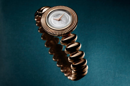 Gold watch with a textured strap on a dark blue background