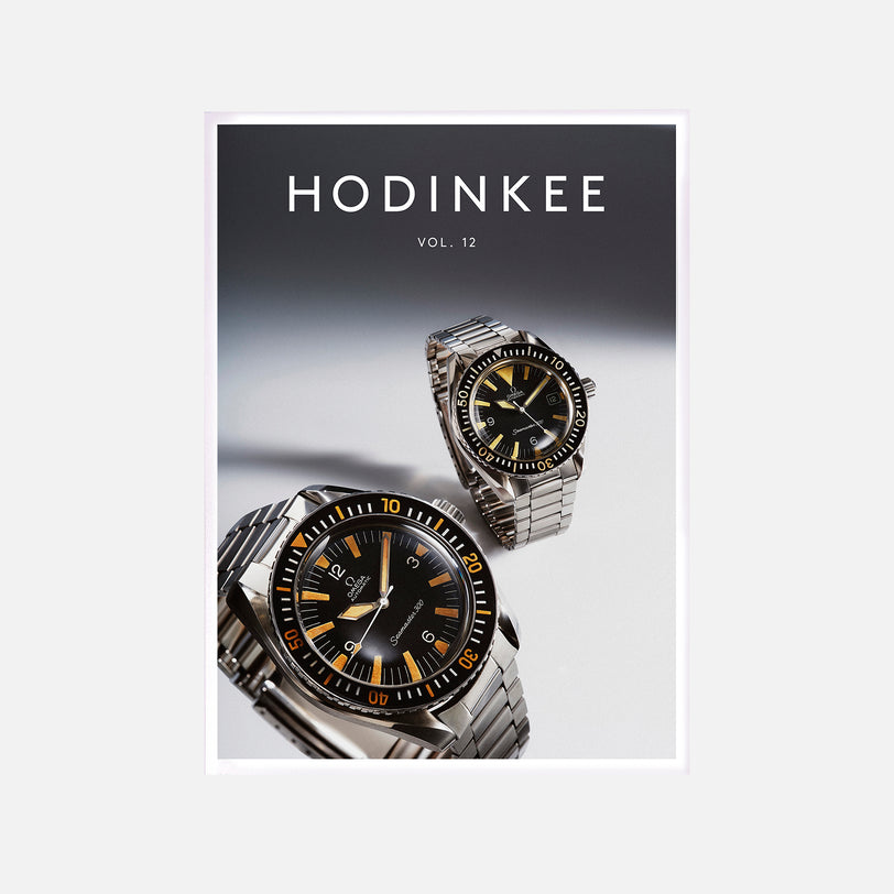 The cover of HODINKEE Magazine, Volume 12 by Hodinkee showcases two stainless steel Omega Seamaster watches with black dials and orange hour markers, celebrating vintage style.