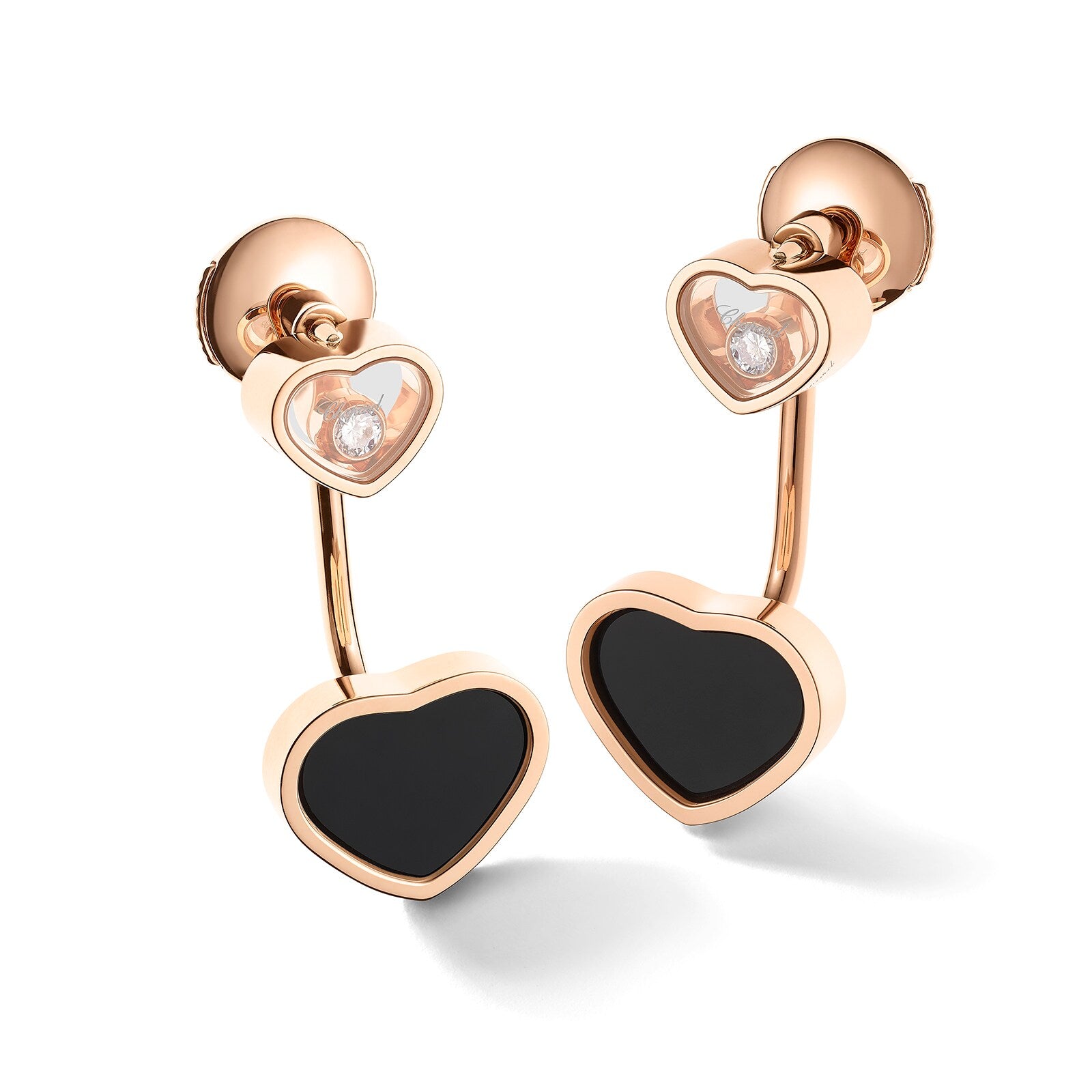 Discover Chopards Happy Diamonds: rose gold heart-shaped earrings featuring black centers and sparkling clear stones above.