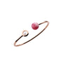 The Chopard Happy Diamonds Planet is a minimalist open bangle in rose gold, featuring a pink stone on one end and a round setting with dancing diamonds on the other.