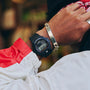Black digital watch with square face and red accents worn on wrist.