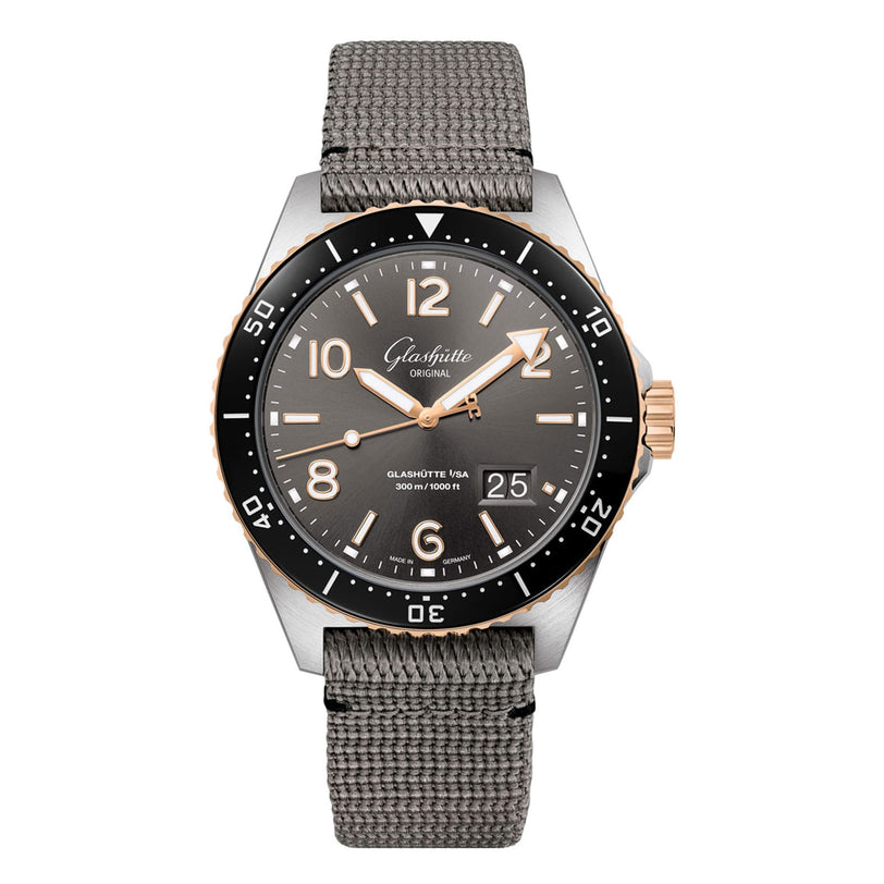 The Glashütte Original SeaQ Panorama Date features a gray dial with gold accents, black bezel, bold white numerals, date window at 4 o’clock, and a robust black cordura-effect rubber strap.