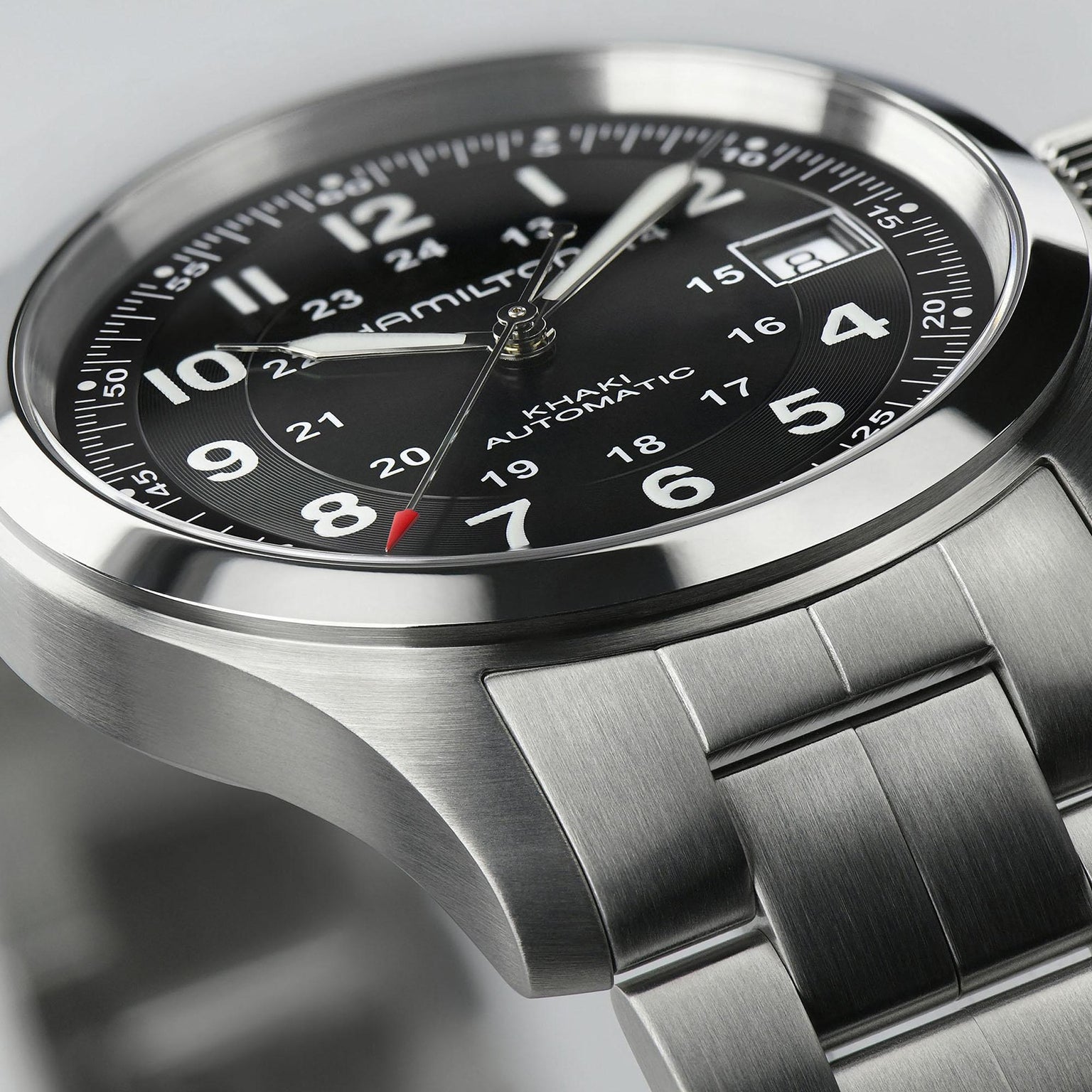 Close-up of the Hamilton Khaki Field Auto, a military-inspired watch with automatic movement, stainless steel band, black dial with Arabic numerals, date window, and 24-hour markings.