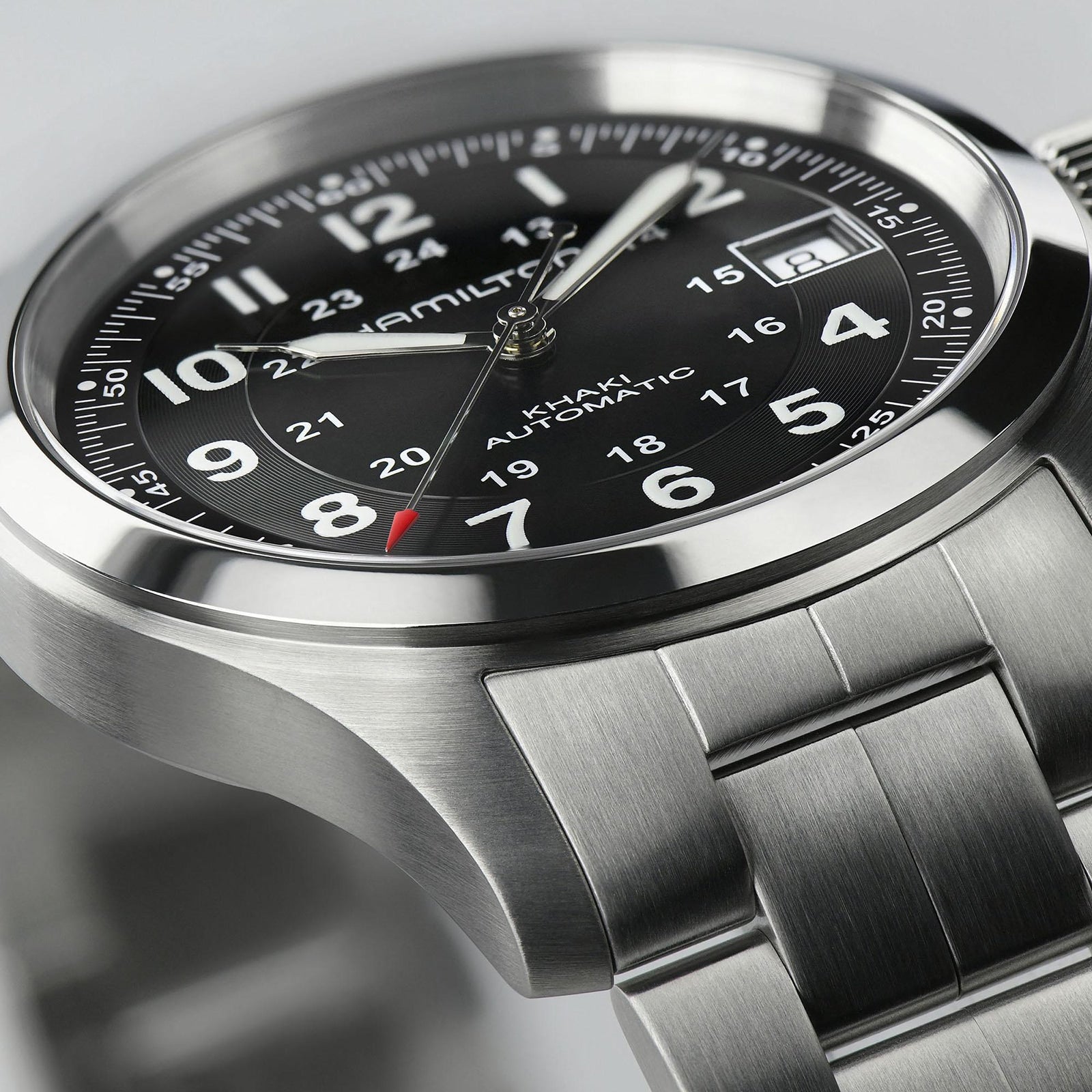 Close-up of the Hamilton Khaki Field Auto, a military-inspired watch with automatic movement, stainless steel band, black dial with Arabic numerals, date window, and 24-hour markings.