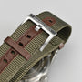 Close-up of a green fabric and brown leather NATO strap with a silver Hamilton-engraved buckle, attached to the stainless steel case of the Hamilton Khaki Field Mechanical 38mm watch.