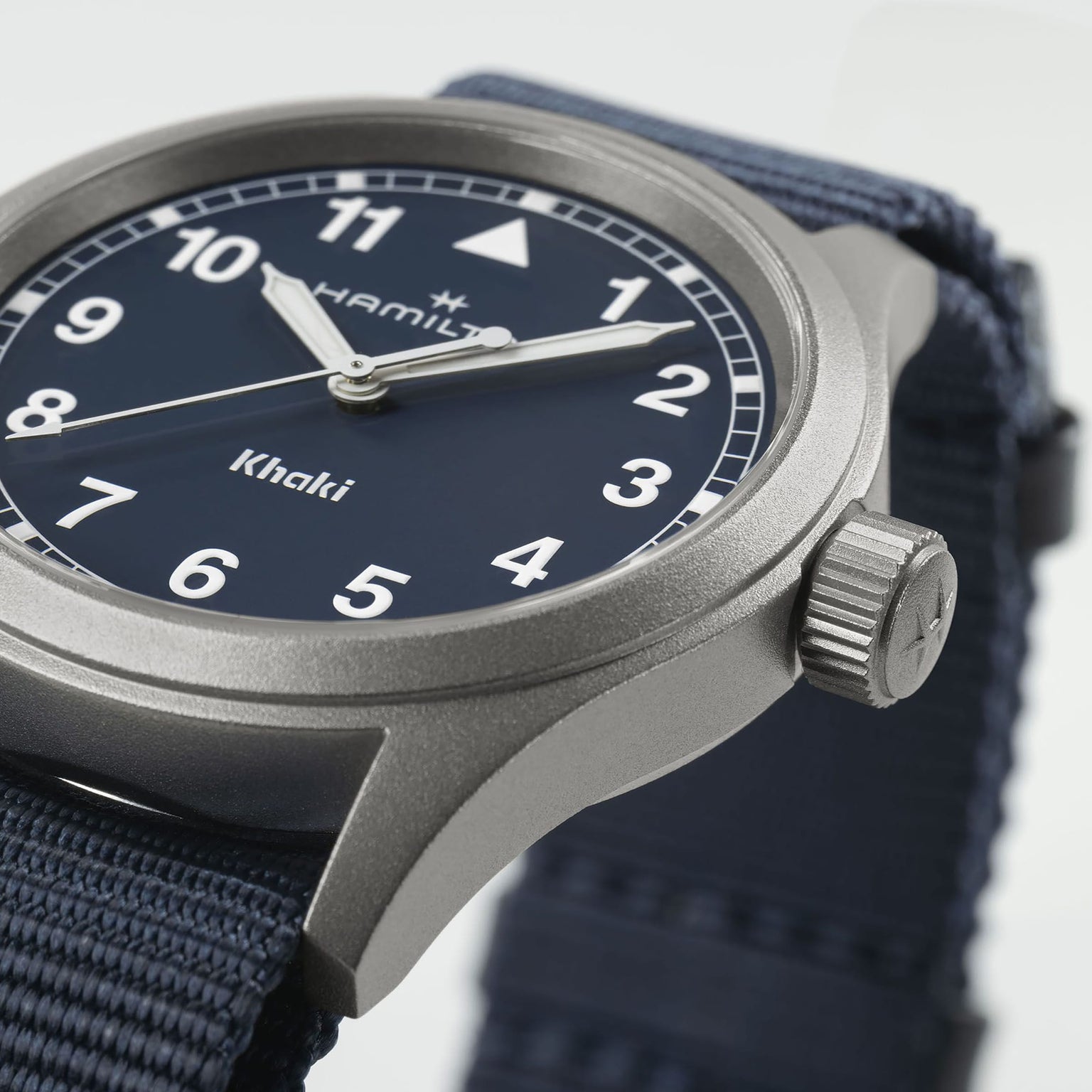 Close-up of the Hamilton Khaki Field Quartz 38mm, featuring a blue dial with white numerals and a robust blue NATO strap—showcasing its military-inspired design. The time on the watch is about 10:09:35.