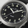 Close-up of a Hamilton Khaki Field Quartz watch showing 10:08, featuring a black dial and luminous hands.