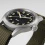Close-up of a Hamilton Khaki Field Quartz watch featuring a black dial and an olive green fabric strap.