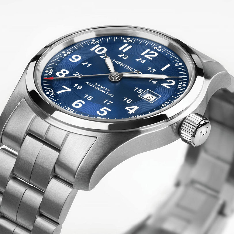 The Hamilton Khaki Field Auto 42mm, featuring a stainless steel case, blue dial with white numerals, H-10 automatic movement, date display, and a metal link bracelet, is angled to highlight its military-inspired design.