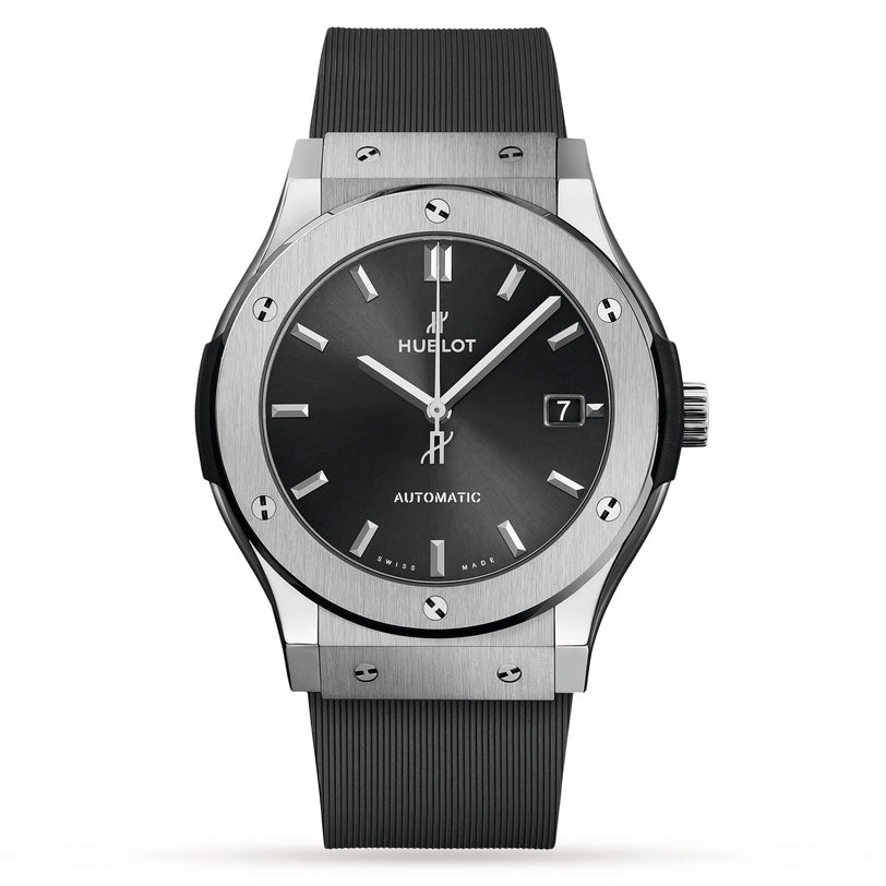 A Hublot Classic Fusion Racing Grey Titanium wristwatch with a black face, silver hour markers, date display at 3 o’clock, titanium case, and black rubber strap.
