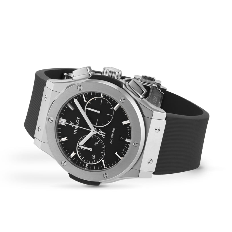 The Hublot Classic Fusion Chronograph Titanium wristwatch features a titanium case, black dial with three subdials and chronograph movement, complemented by a black rubber strap and shown against a white background.