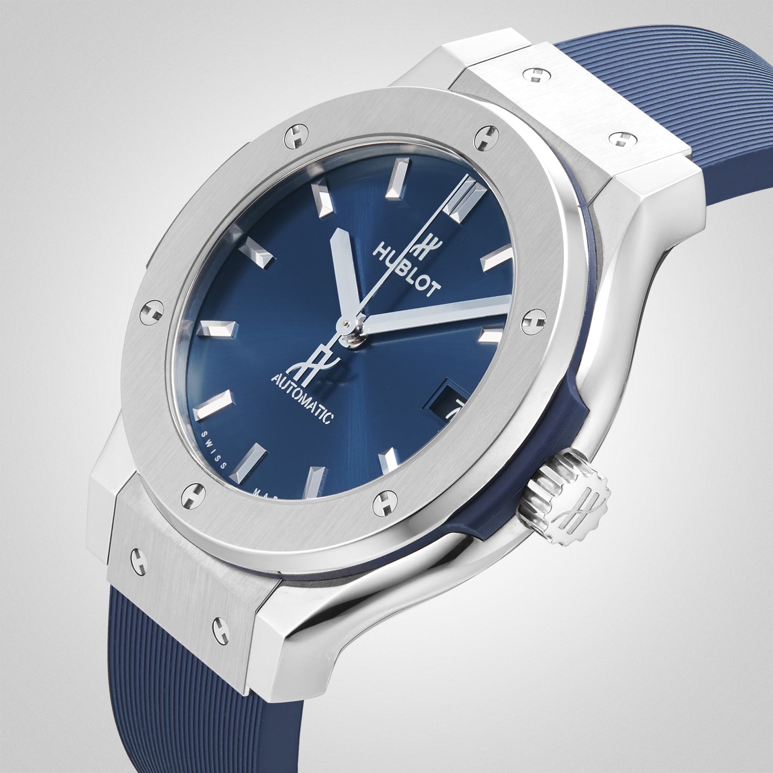 The Hublot Classic Fusion Titanium Blue wristwatch features a sleek titanium case, blue dial, silver hour markers, date display, and a blue strap, displayed against a plain light background.