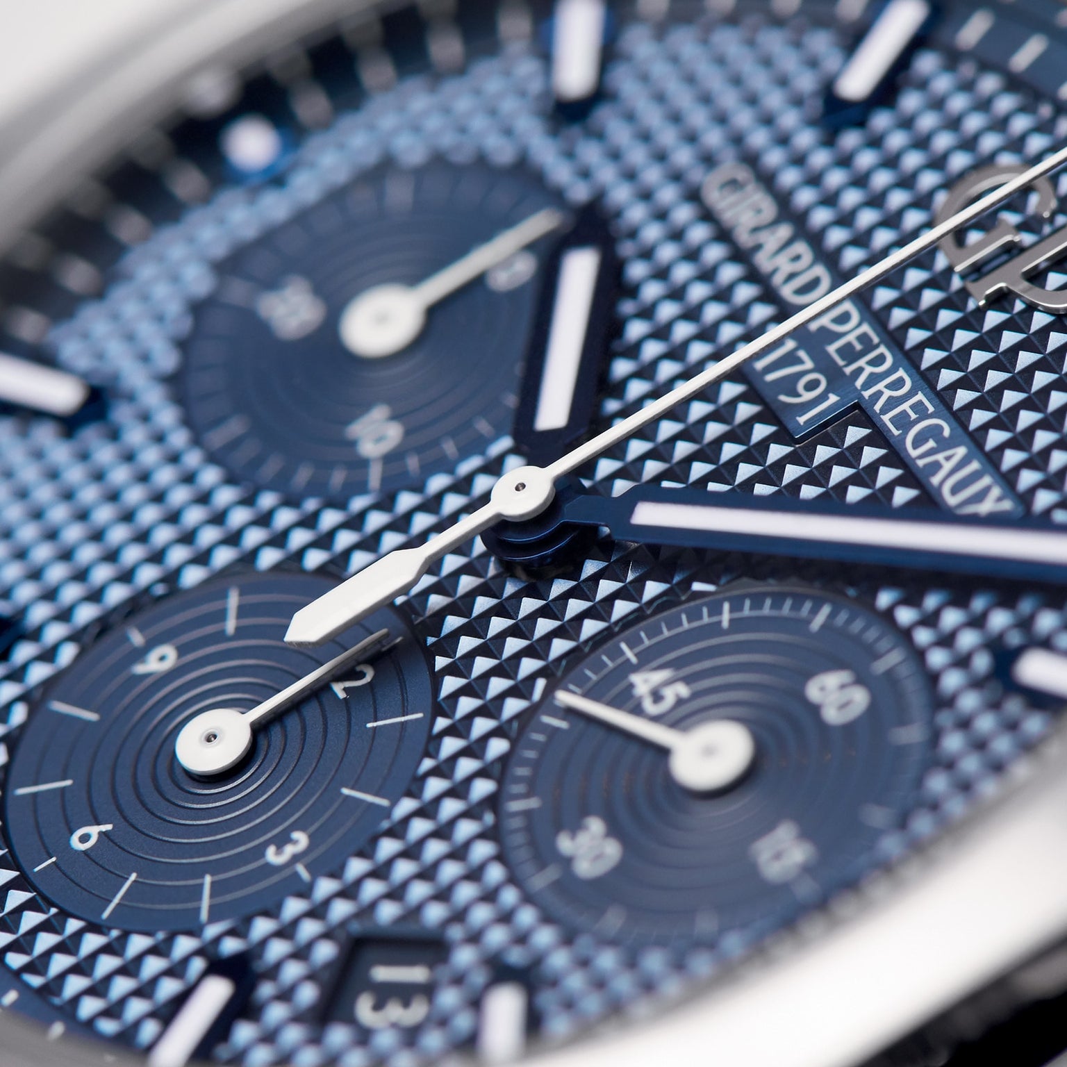 Close-up of the Girard-Perregaux Laureato Chronograph 42, highlighting its blue textured dial, octagonal bezel, subdials, silver hands, and prominent branding.