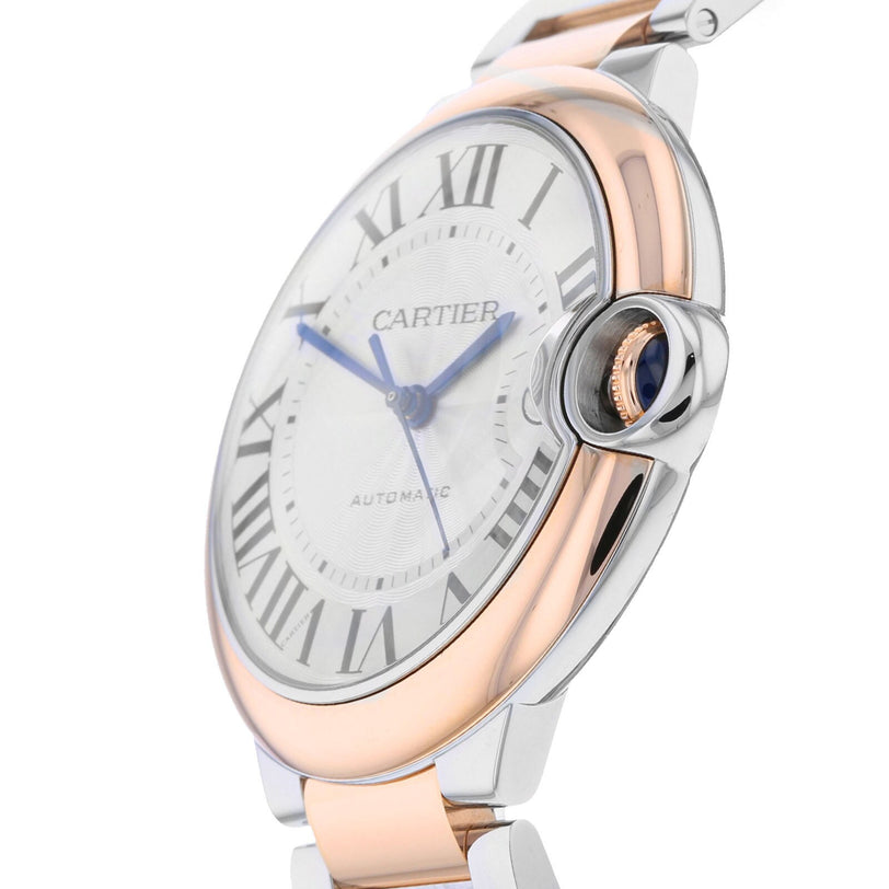 A close-up of the Ballon Bleu de Cartier by Cartier, showcasing its round two-tone case, Roman numerals, blue hands, and a distinctive crown set with a blue cabochon.