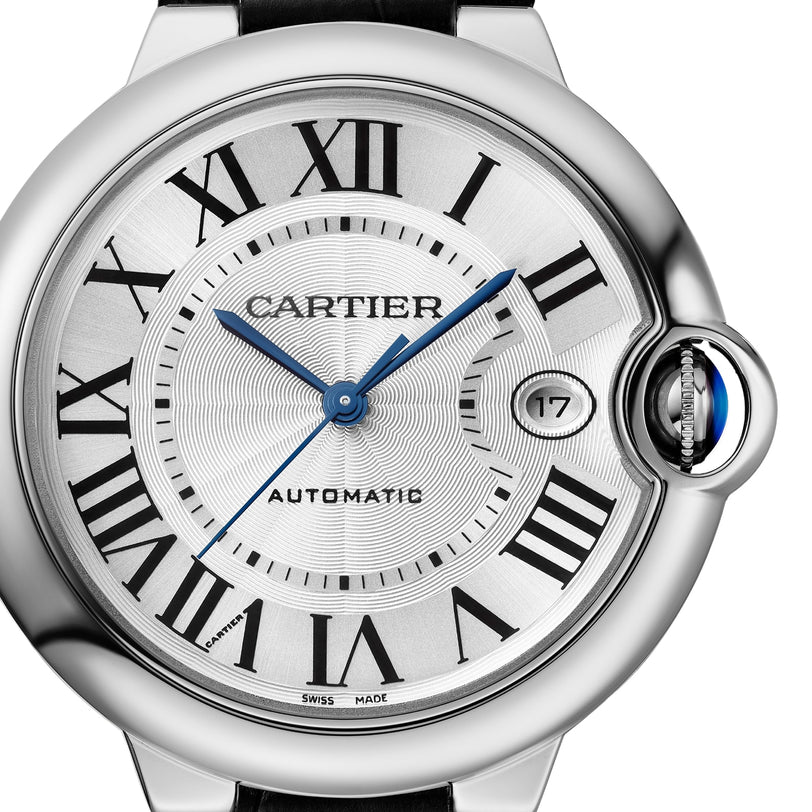 Close-up of a Cartier Ballon Bleu de Cartier automatic watch with a silver dial, Roman numerals, blue hands, date at 3 o’clock, crown set with blue cabochon, interchangeable bracelet, and signature mechanical movement.