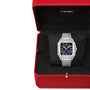 A Cartier Santos de Cartier wristwatch with a blue dial, square silver steel case, and Roman numerals is showcased inside a red Cartier box featuring black interior lining.