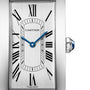 Close-up of the Cartier Tank Américaine watch face, featuring blue hands, Roman numeral hour markers, and a silver background. The crown is adorned with a blue gemstone, reflecting Cartiers signature elegance.