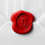 A white envelope sealed with a red wax seal embossed with Cartier’s interlocking double C logo, echoing the refined elegance and timeless style of the Tank Américaine.
