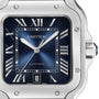 Close-up of the Santos de Cartier by Cartier, an aviation watch with a square blue dial, Roman numerals, date at 6 o’clock, stainless steel case, and mechanical movement.