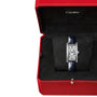 The Cartier Tank Américaine wristwatch, featuring a rectangular design and blue leather strap, is elegantly displayed in an open red Cartier box with black interior lining, embodying the brand’s timeless sophistication.