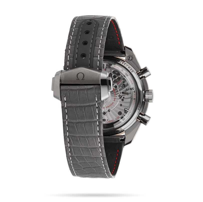 A close-up of the OMEGA Speedmaster Dark Side of the Moon Meteorite shows its automatic movement through a ceramic case, with a grey leather strap and OMEGA branding on the clasp.
