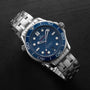 An OMEGA Seamaster Diver 300M stainless steel watch with a blue dial and bezel, silver hour markers, and metal bracelet featuring the Master Chronometer Calibre 8800, shown on a dark surface.