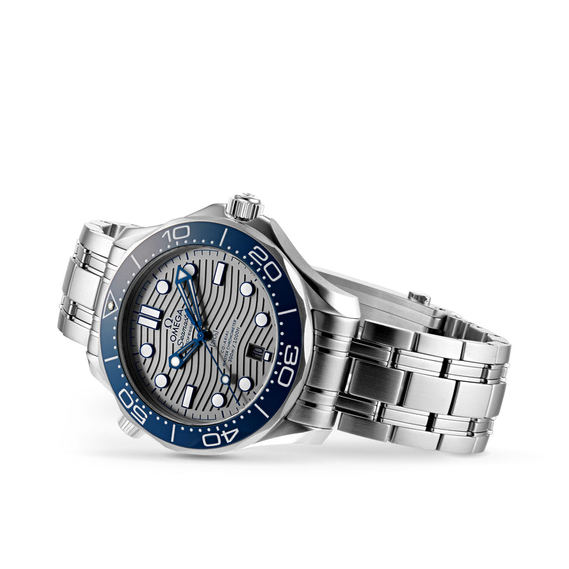 An OMEGA Seamaster Diver 300M stainless steel watch with a blue bezel, silver wave-pattern dial, and luminous markers, inspired by the James Bond watch, shown on its side against a white background.