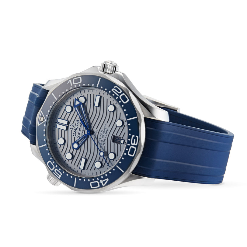 The OMEGA Seamaster Diver 300M, with a silver wavy-patterned dial, blue bezel, and blue rubber strap featuring the Calibre 8800, is shown angled on a white background.