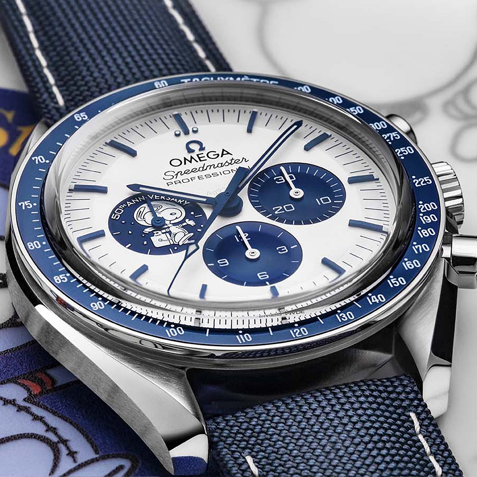 A close-up of the OMEGA Speedmaster Snoopy Award Anniversary Series watch with blue and white accents, Snoopy illustration, chronograph subdials, and a tribute to the Silver Snoopy Award—showcasing its iconic Speedmaster legacy.