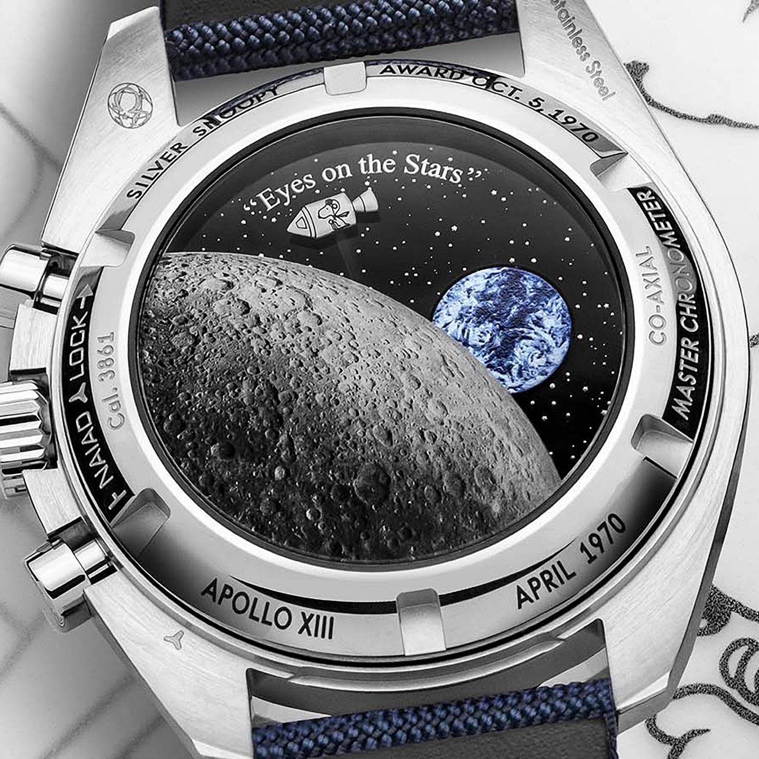 The OMEGA Speedmaster Snoopy Award Anniversary Series features a caseback engraved with the Moon, Earth, and Eyes on the Stars, celebrating its Apollo XIII heritage and connection to the Silver Snoopy Award.