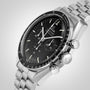 The OMEGA Speedmaster Moonwatch Professional in stainless steel features a black dial, chronograph subdials, tachymeter bezel, and metal bracelet—photographed on a light background as a tribute to the iconic 4th generation design.