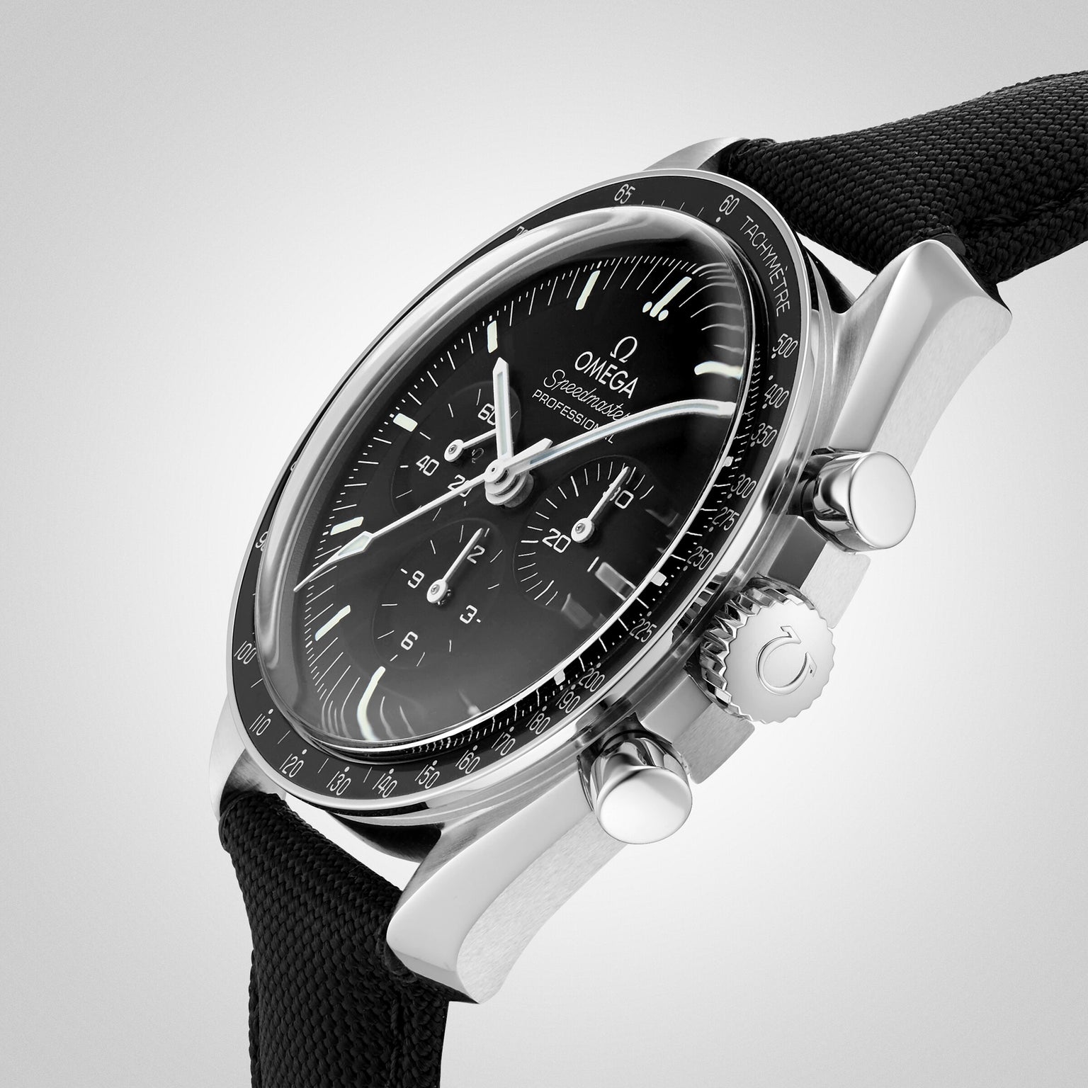A close-up of the OMEGA Speedmaster Moonwatch Professional with a black dial, chronograph functions, and a black fabric strap—an iconic tribute to the first watch on the moon—set against a light gray background.