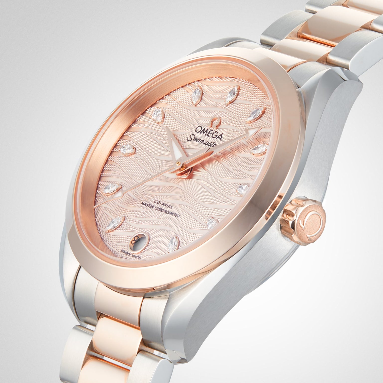 A close-up of an OMEGA Seamaster Aqua Terra 150M wristwatch with a rose gold and silver band, a rose gold bezel, and a textured pink dial adorned with diamond hour markers.