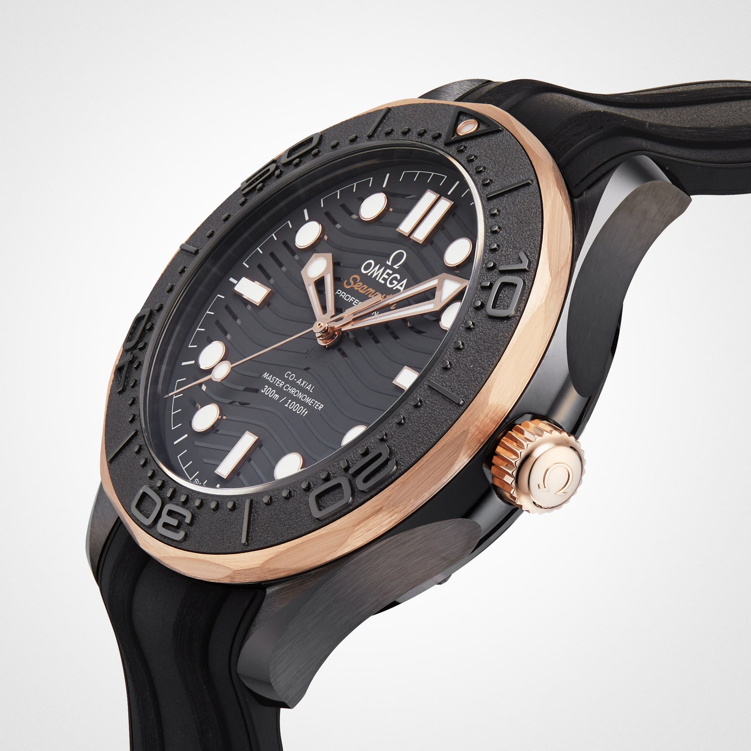 Close-up of an OMEGA Seamaster Diver 300M wristwatch with black dial, gold accents, black bezel, and rubber strap, featuring the OMEGA Calibre 8806 movement, captured against a light background.