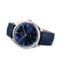 The OMEGA De Ville Trésor, featuring a blue sunburst dial, silver hour markers, and a blue leather strap, rests on its side against a white background. It is powered by the OMEGA Co-Axial Calibre 8926 Master Chronometer movement.