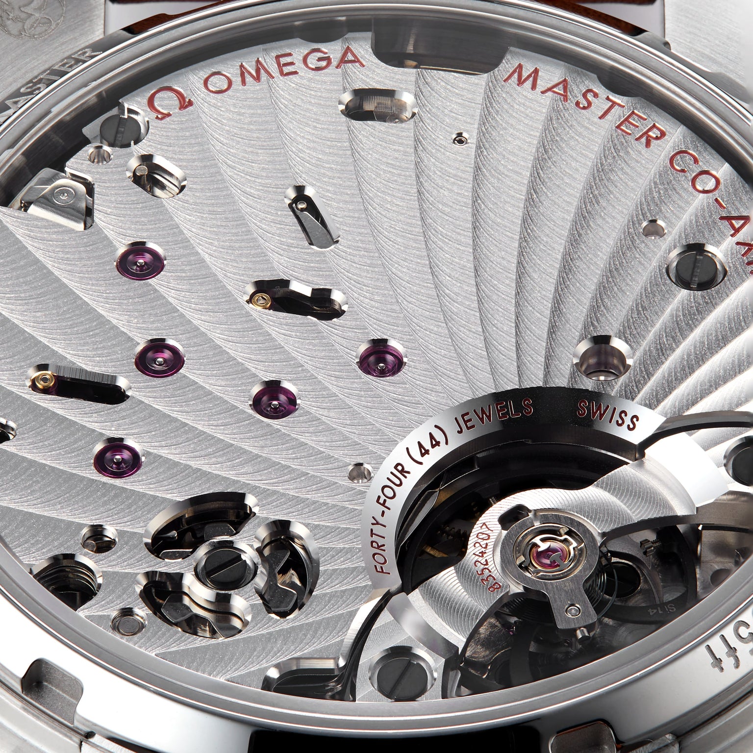 Close-up of an OMEGA Speedmaster Chronoscope movement highlighting intricate gears, jewels, and engraved text such as MASTER CO-AXIAL, FORTY-FOUR (44) JEWELS, and SWISS.