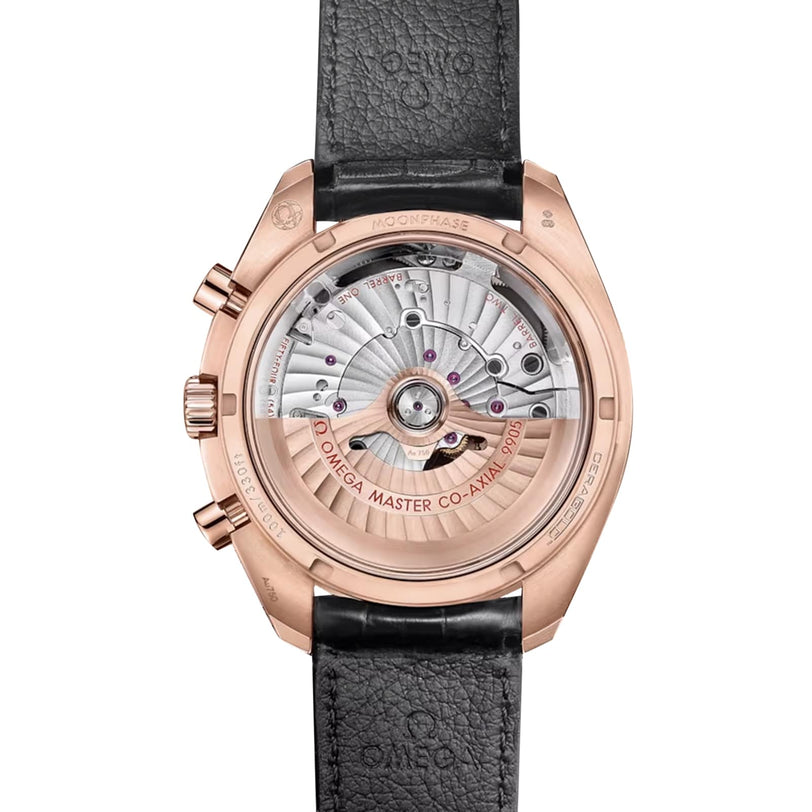 The back of the OMEGA Speedmaster Moonphase 44 shows its exposed mechanical movement, complemented by a black leather strap, Omega Master Co-Axial labeling, and elegant accents of 18K Sedna™ gold.
