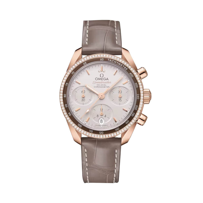 The OMEGA Speedmaster 38 chronograph features 18K Sedna™ gold, a grey alligator strap, silver dial with diamond bezel, three subdials, and a Co-Axial Calibre 3330 movement, displayed on a plain white background.