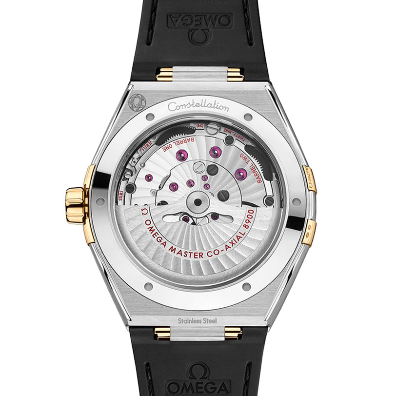 Close-up of the back of the OMEGA Constellation watch, highlighting its master chronometer-certified 8900 calibre movement with engraved details, gold accents, and a black strap.