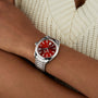 A person in a cream-colored knit top wears an OMEGA Seamaster Aqua Terra 150M with a silver case, red dial, and date display.