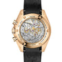 Back view of the OMEGA Speedmaster Moonwatch Professional, showing its exposed mechanical movement, gold case, black leather strap, and engraved text around the edge.